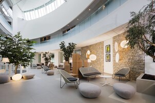 Un espacio interior amplio con asientos modernos, una pared de piedra y un techo de cristal.