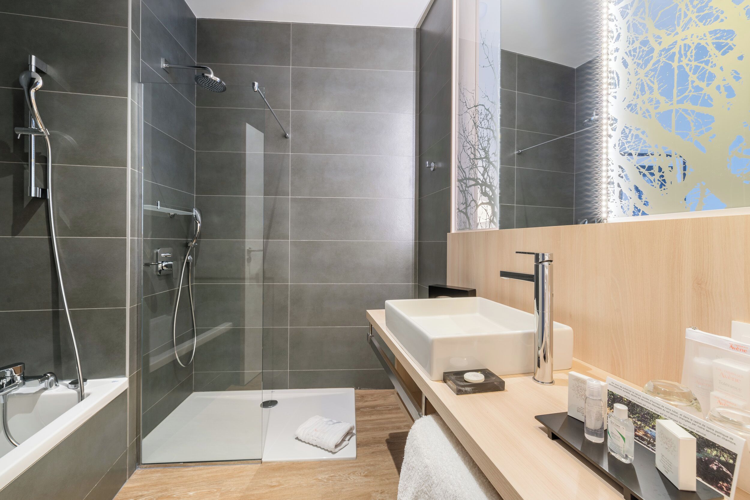 Une salle de bain moderne dotée d’une douche à parois de verre, d’une baignoire sur pieds et d’un meuble-lavabo avec un grand miroir.