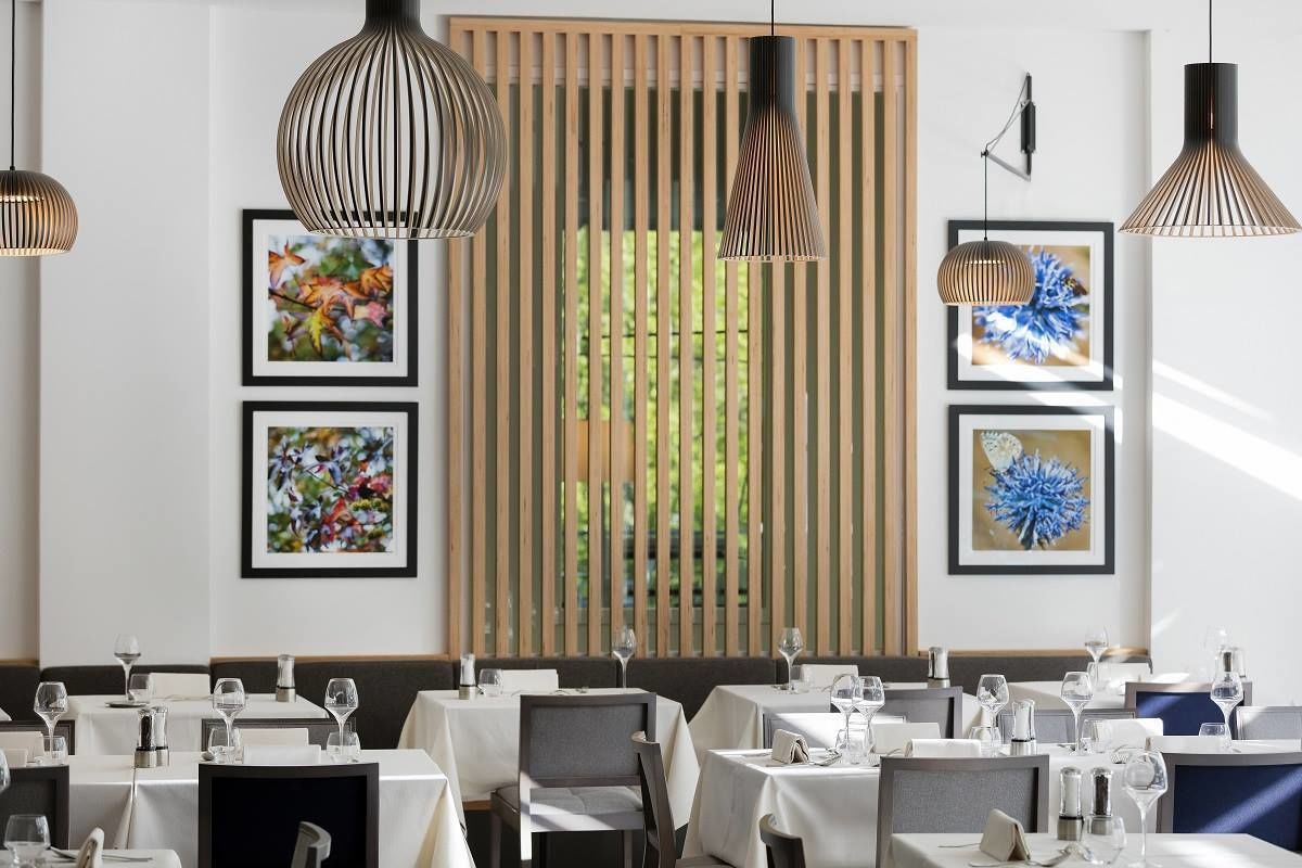 A restaurant with tables set for dining, framed artwork on the walls, and hanging pendant lights.