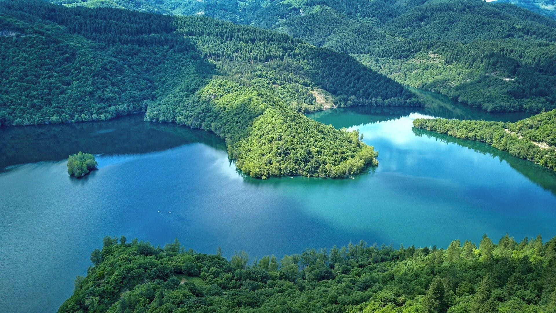 A serene lake surrounded by dense forested hills.
