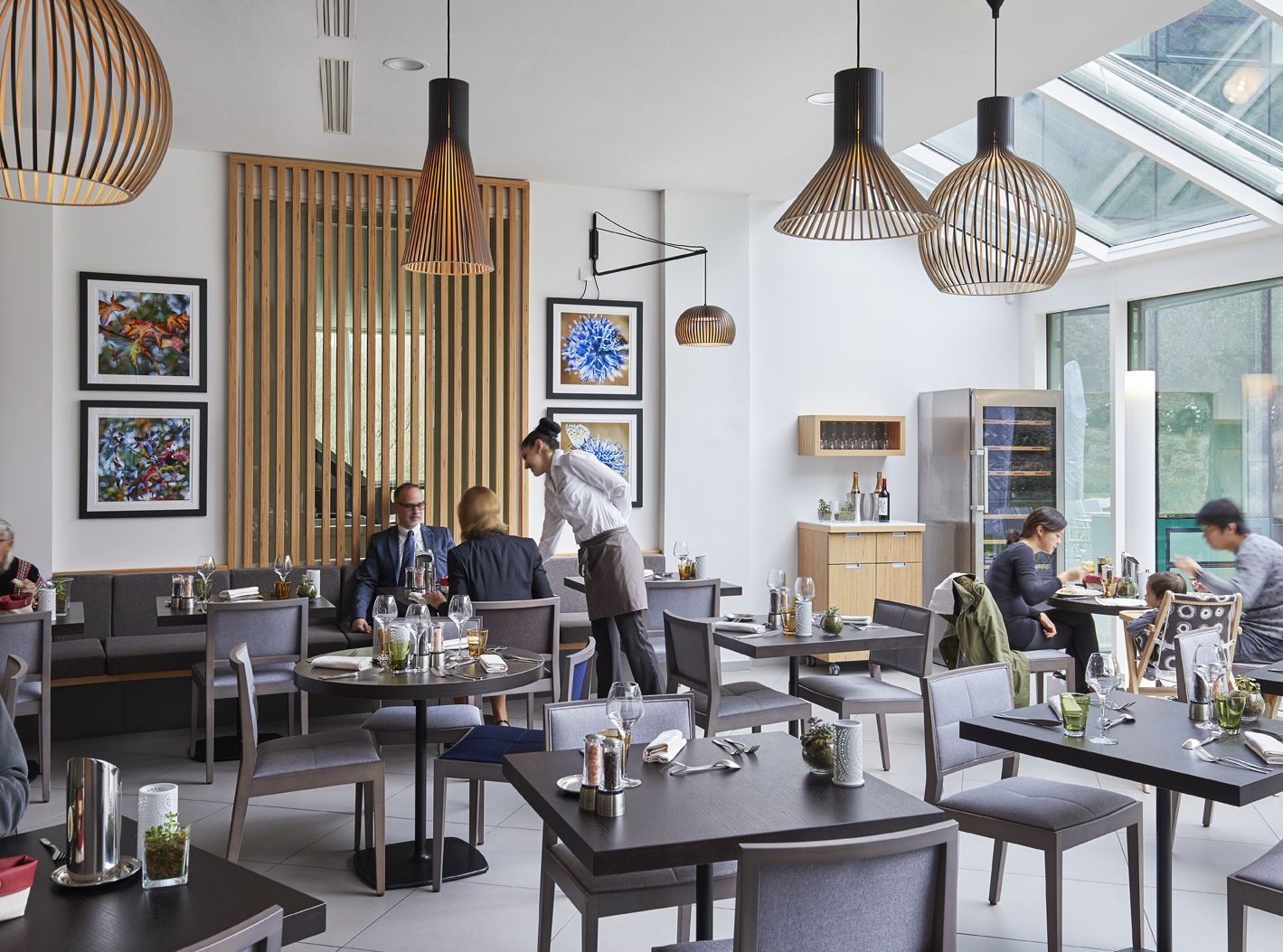 A modern dining area with round tables, pendant lighting, and artwork on the walls.