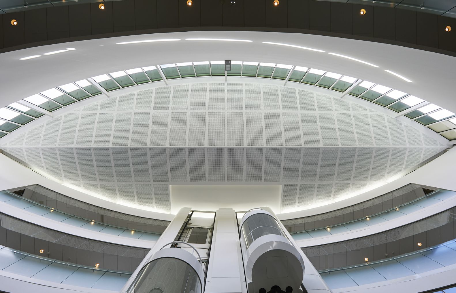 Een modern, circulair gebouw met een glazen dak en meerdere verdiepingen.