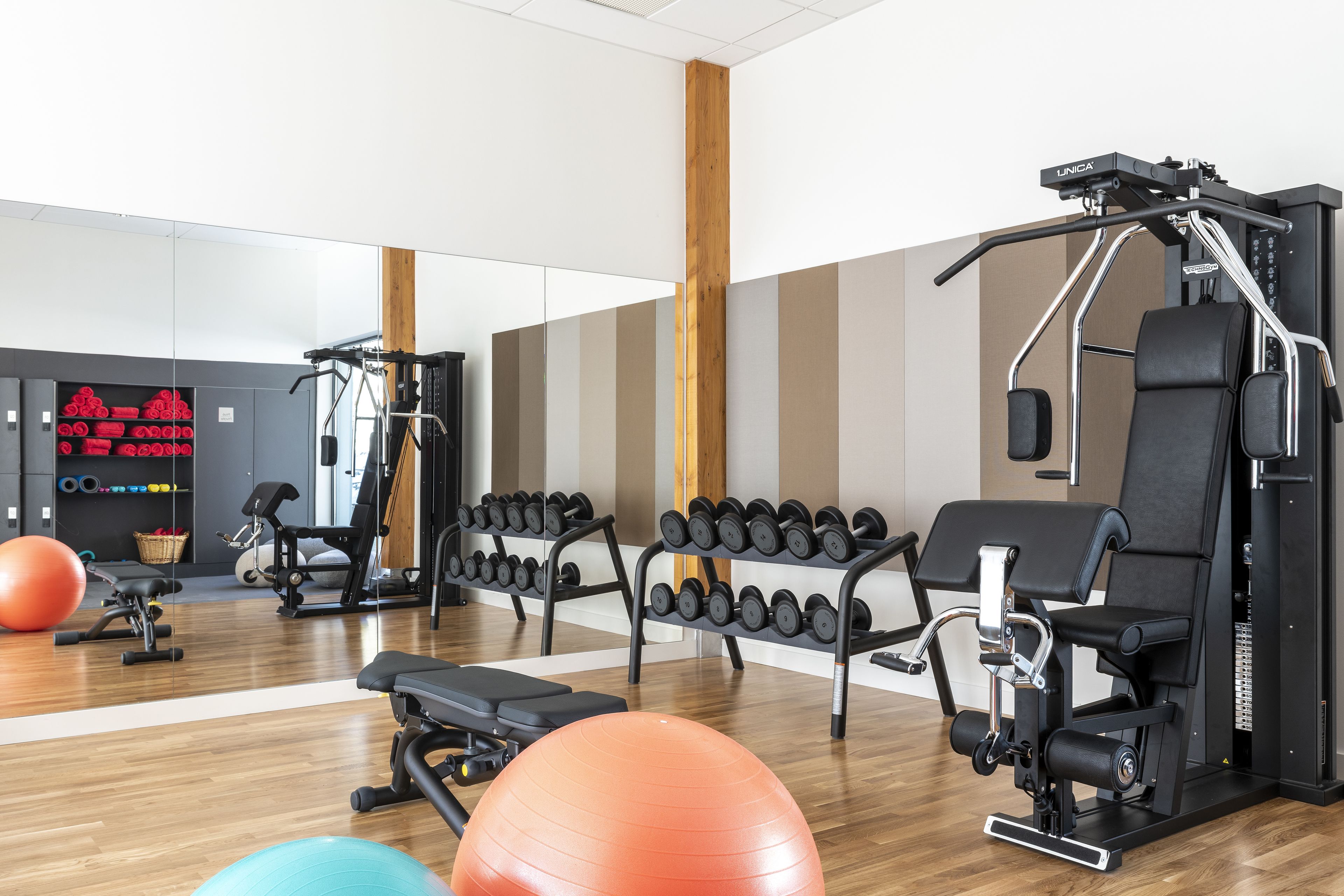 Un gimnasio con equipo de ejercicio, mancuernas y pelotas de entrenamiento.