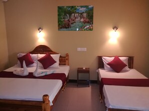 Habitación de hotel con dos camas, cada una con cabecero de madera, ropa de cama blanca y almohadas rojas. Hay un cuadro de una cascada en la pared, y dos lámparas de pared.