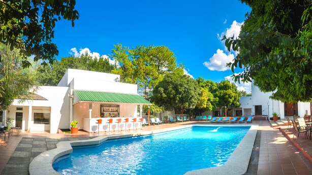 Un espace piscine avec des chaises longues, un bar et un bâtiment doté d’un toit végétalisé.