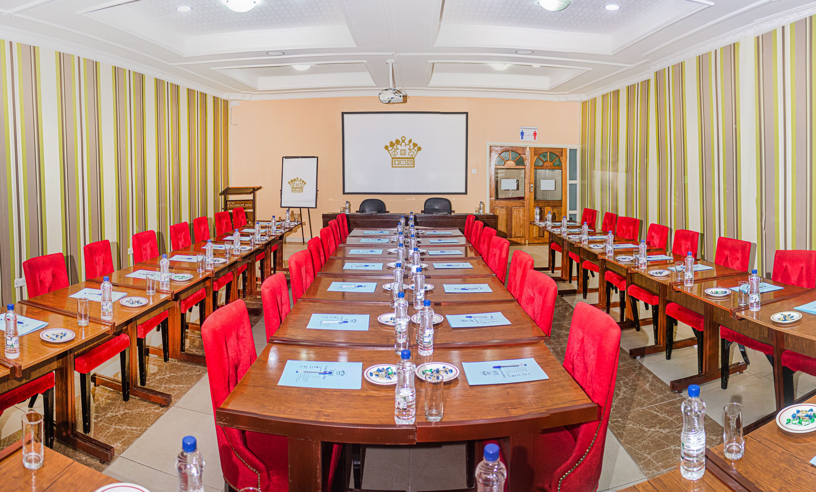 A conference room with long tables, red chairs, and water bottles.
