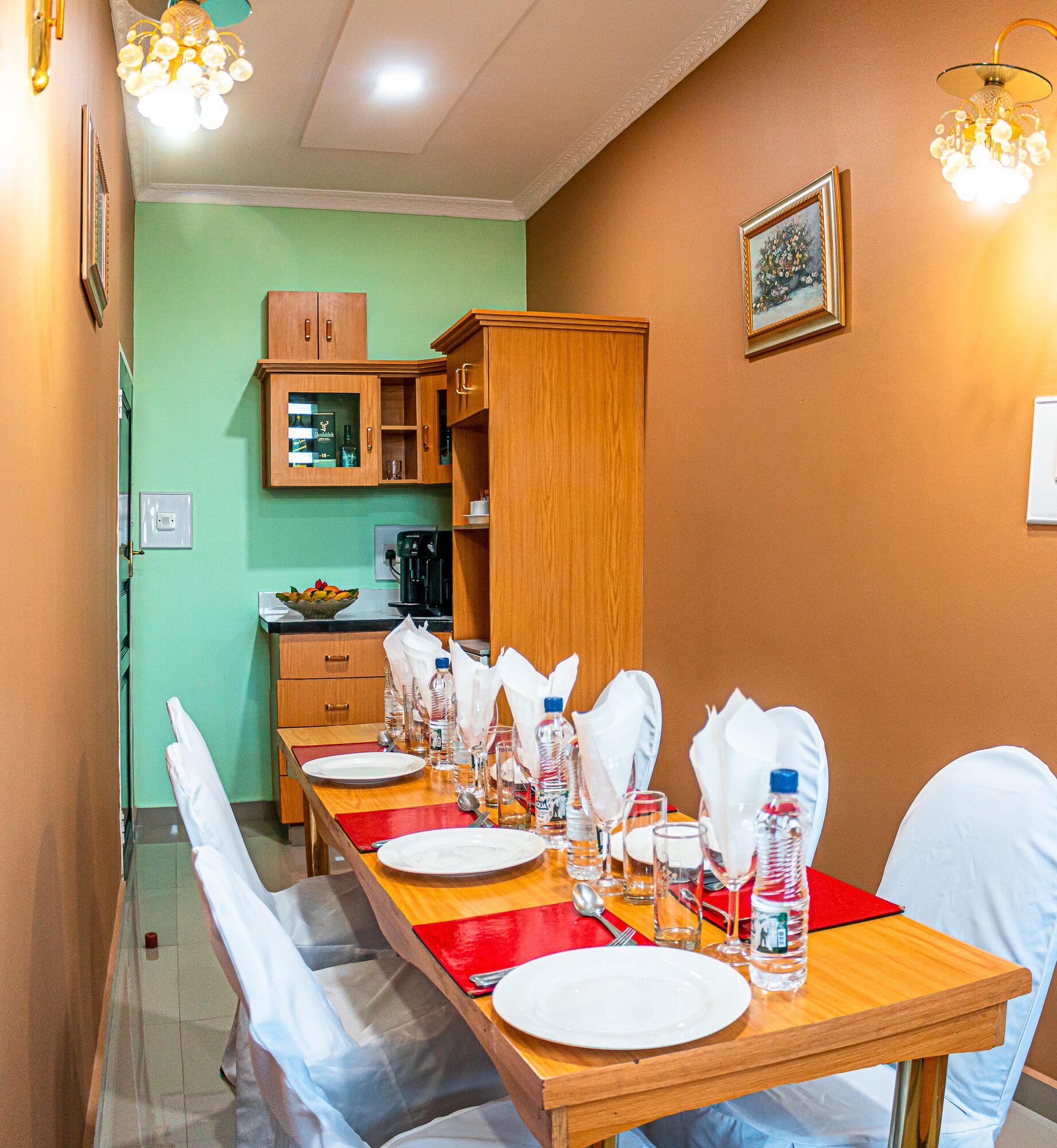 A dining area with a long wooden table set for a meal, equipped with plates, glasses, and cutlery.