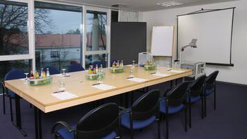 A conference room with a long table, chairs, a projector screen, and a whiteboard.