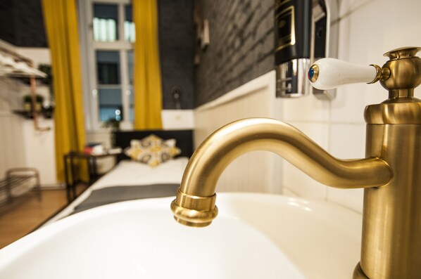 Une salle de bain avec un robinet doré et un lavabo blanc.