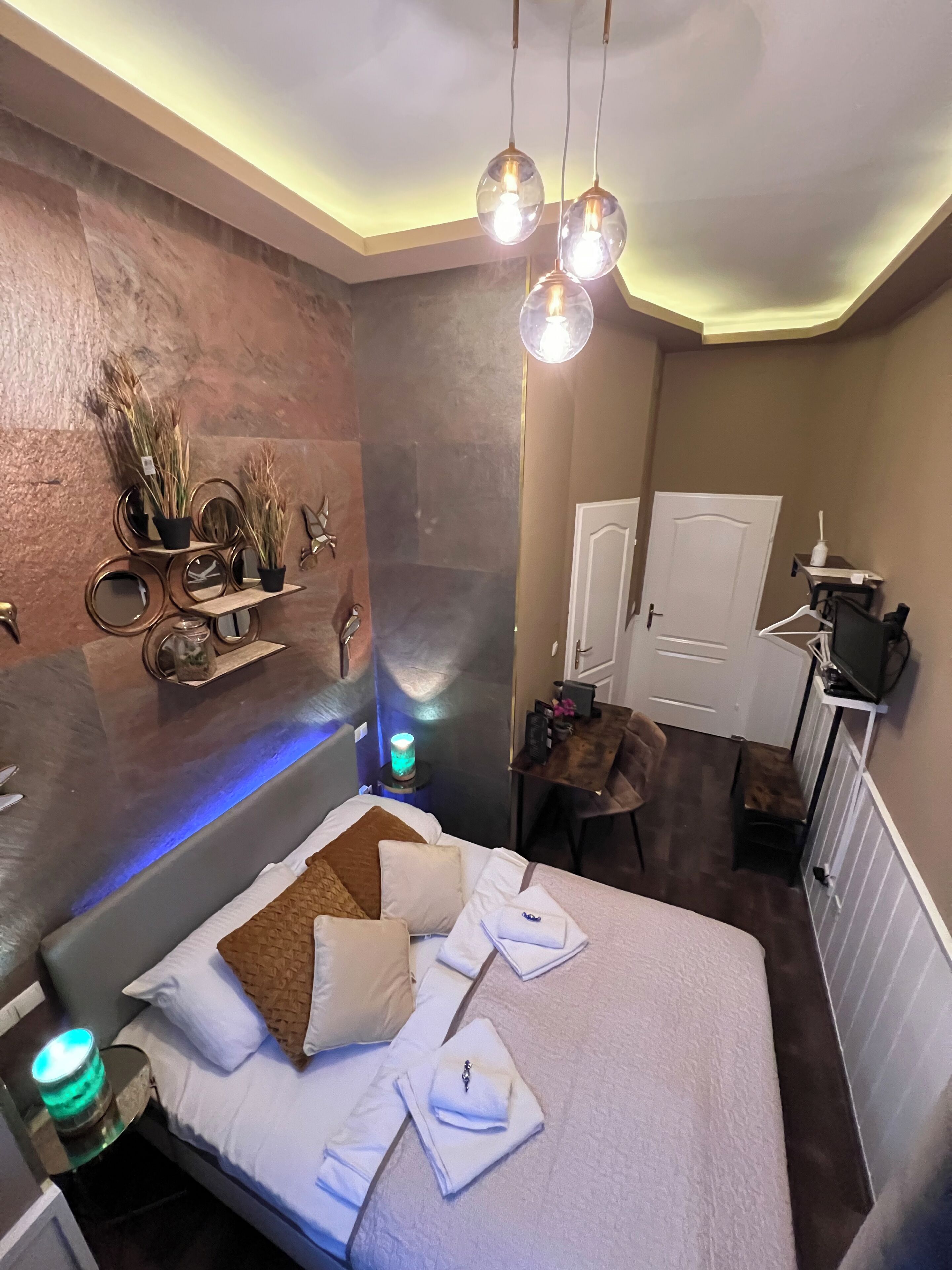 A modern bedroom with a bed, bedside lamps, a mirror, and a small desk with a chair.