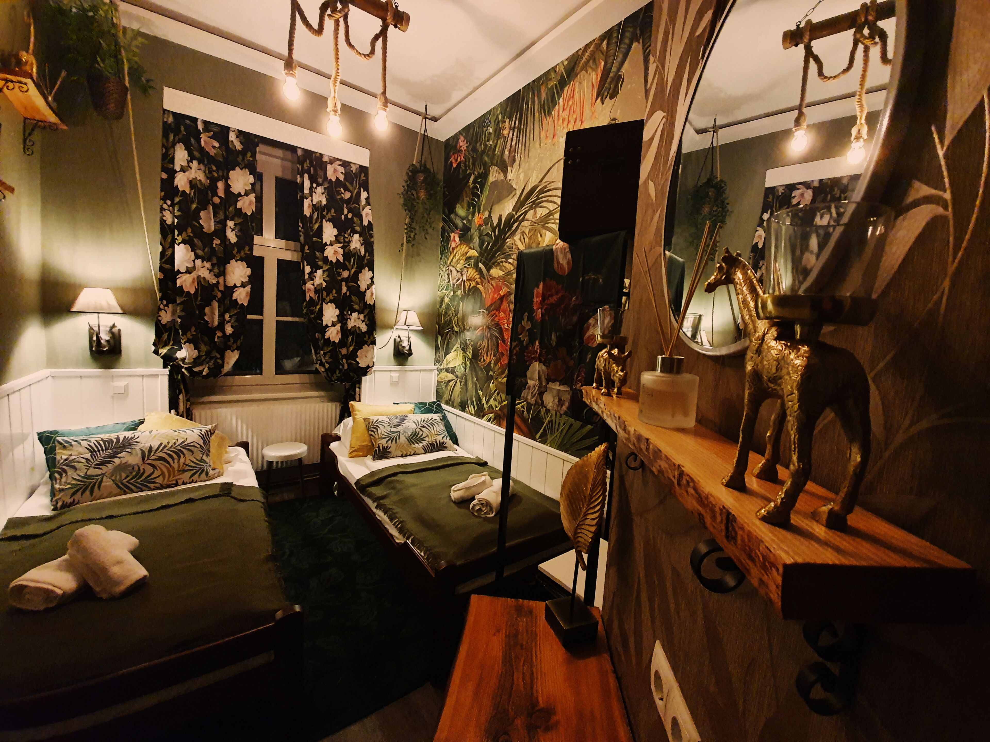 A cozy bedroom with a bed, bedside tables, a mirror, and a dresser.