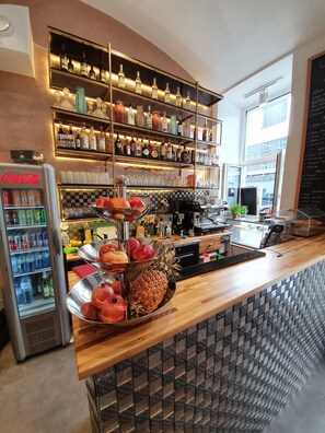 A bar area with shelves of liquor bottles, a Coca-Cola cooler, and a fruit display. - Urban Boutique Hotel (Vienna)