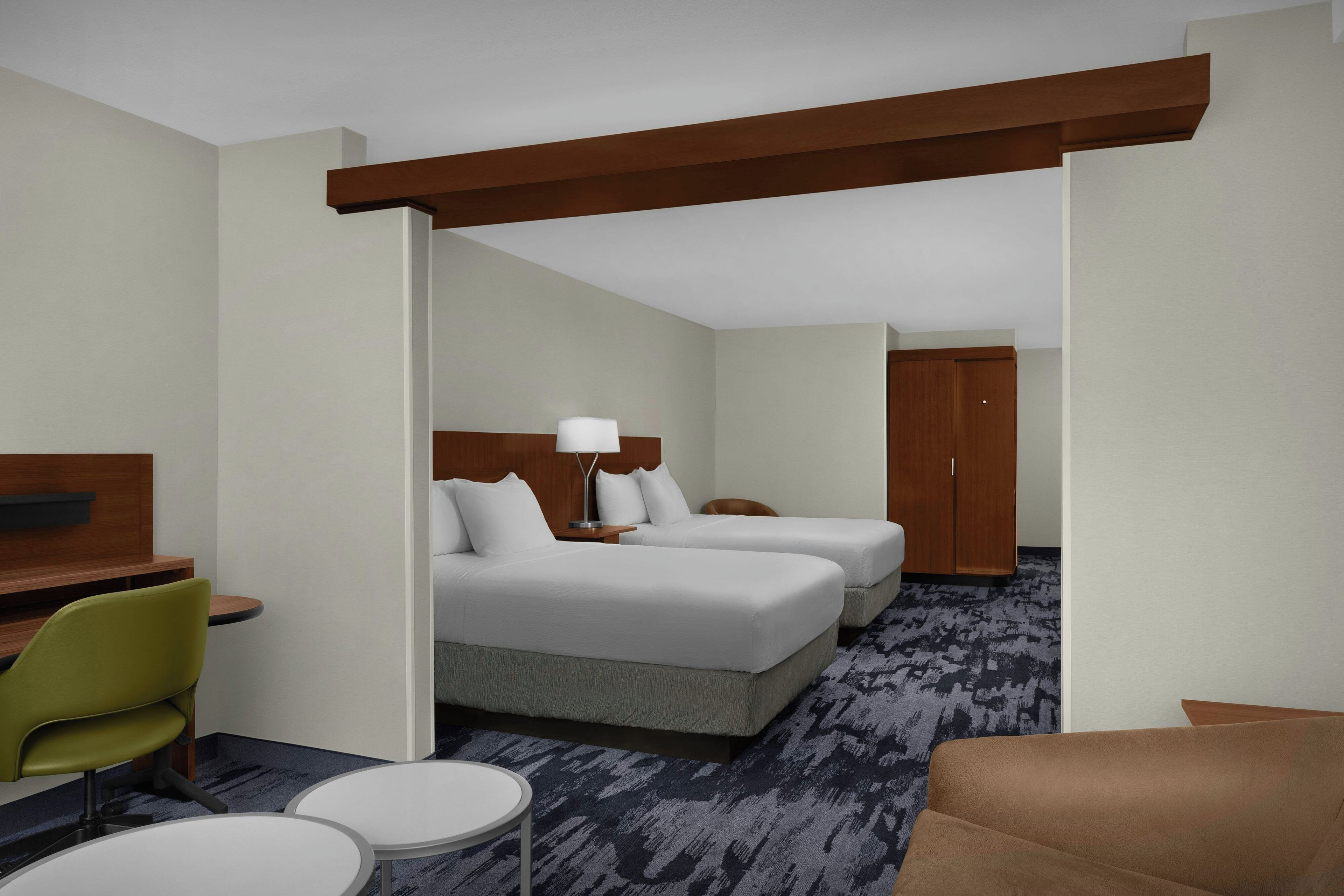 Una habitación de hotel con una cama, dos mesitas de noche, un escritorio, una silla y un armario.