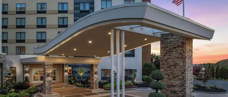 A Fairfield by Marriott hotel entrance with a covered walkway, stone pillars, and a landscaped garden.