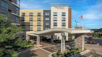 Fairfield by Marriott -hotellin sisäänkäynti, jossa on katettu käytävä, lippu ja maisemoitu alue.