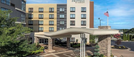 A Fairfield by Marriott hotel entrance with a covered walkway, flag, and landscaped area.