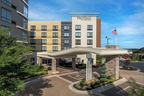 A Fairfield by Marriott hotel entrance with a covered walkway, flag, and landscaped area. - Fairfield Inn & Suites Atlanta Lithia Springs (Lithia Springs)
