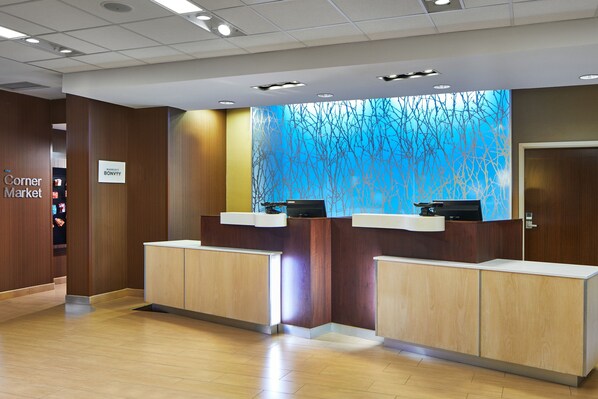 A reception area with wooden paneling, a blue abstract wall, and a sign reading "Corner Market". - Fairfield Inn & Suites Atlanta Lithia Springs (Lithia Springs)