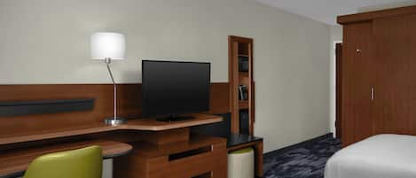 A hotel room with a wooden desk, a television, a green chair, a wardrobe, and a bed.