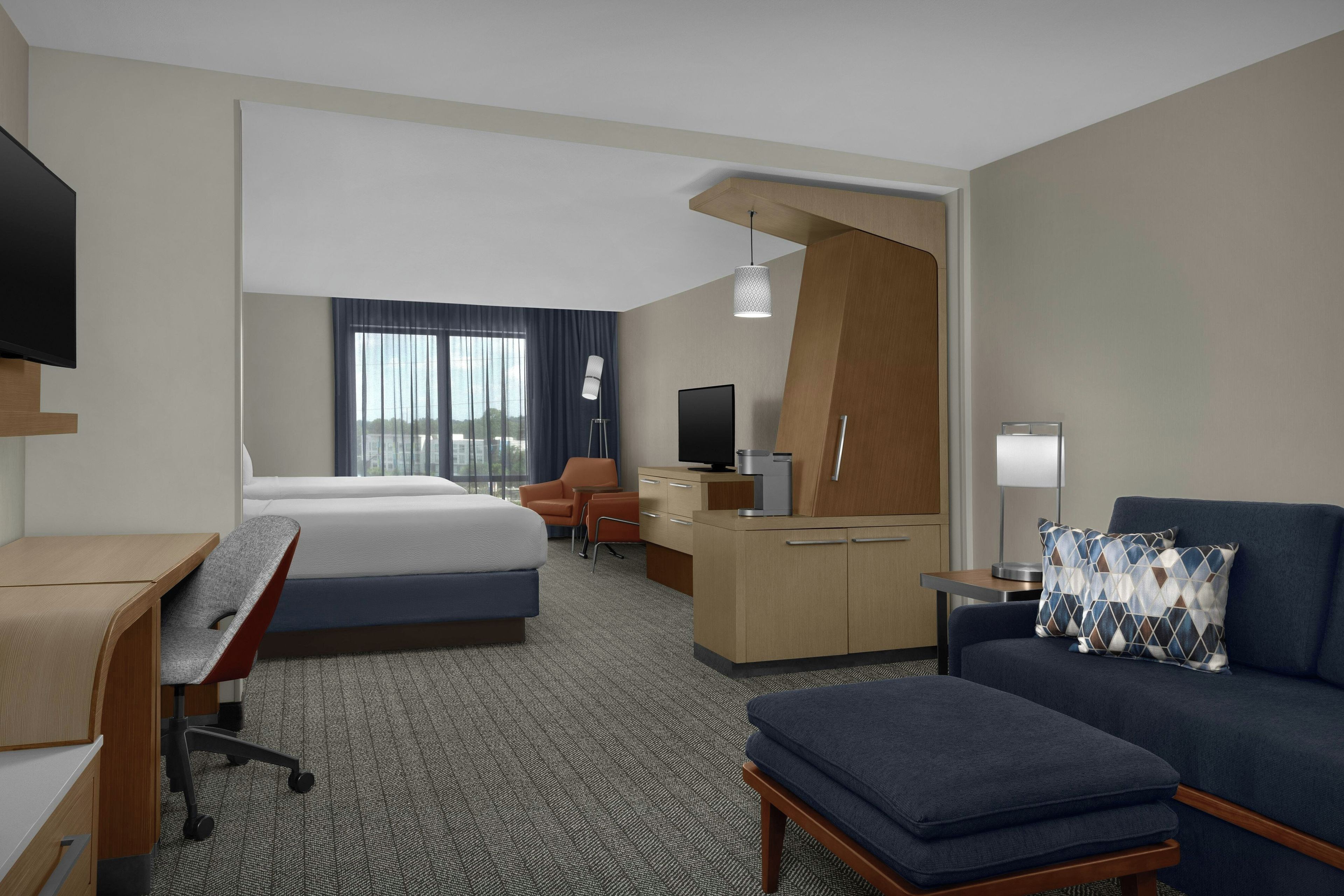Een hotelkamer met een bed, bureau, stoel, bank en een televisie.
