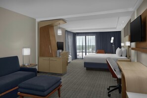 A hotel room with a bed, a desk, a sofa, a TV, and a large window with curtains. - Courtyard by Marriott Atlanta Lithia Springs (Lithia Springs)