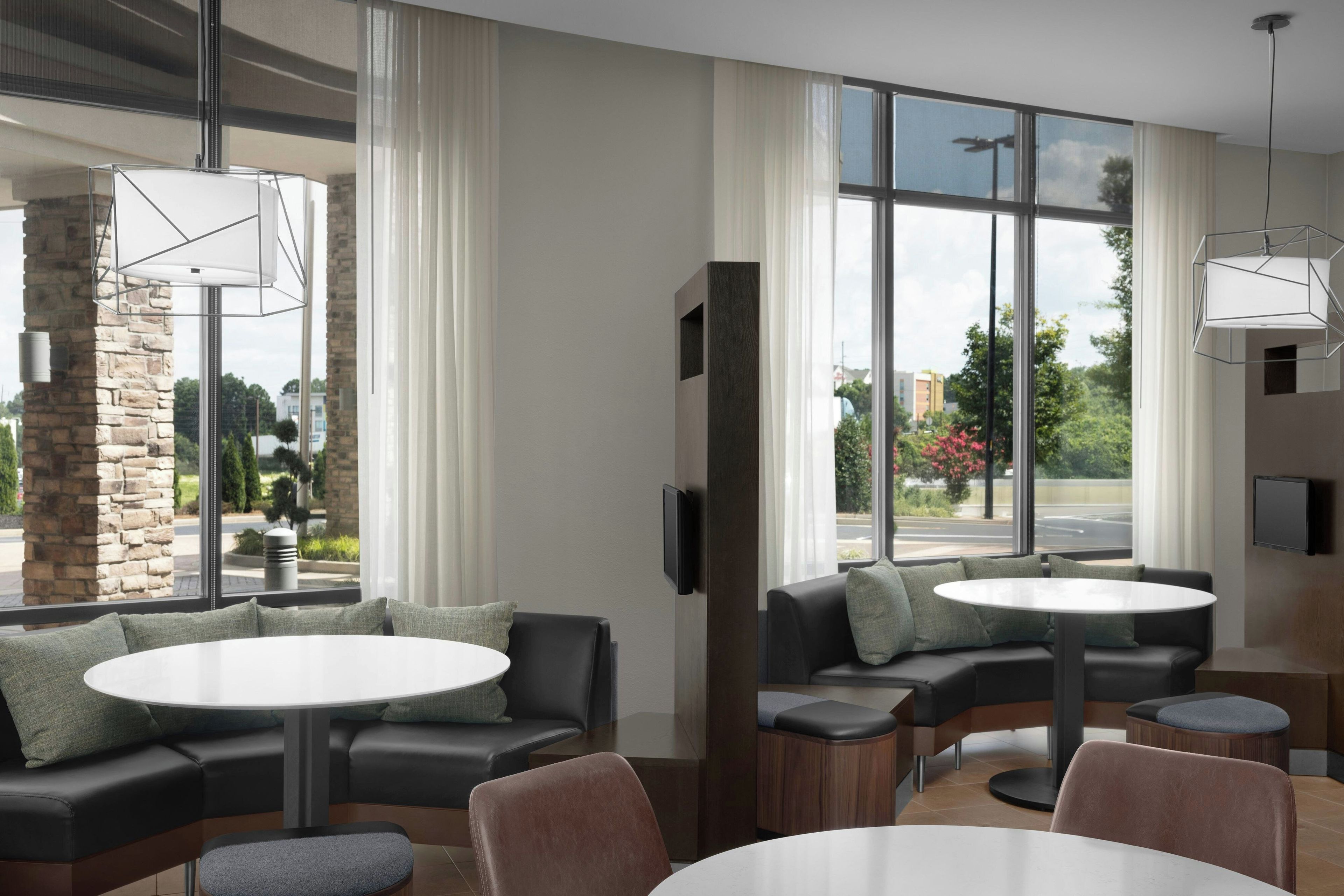 Un interior moderno con un sofá modular, mesas redondas y grandes ventanales que ofrecen vistas al exterior.