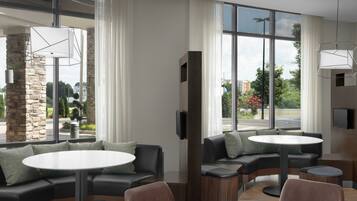 Un interior moderno con un sofá modular, mesas redondas y grandes ventanales que ofrecen vistas al exterior.