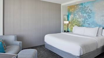 Habitación de hotel con una cama, una silla, una mesa y una pared decorada con un cuadro.