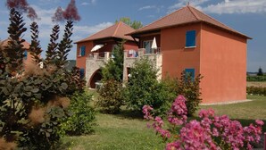 Un edificio de dos pisos con techo rojo y una entrada con arco de piedra.