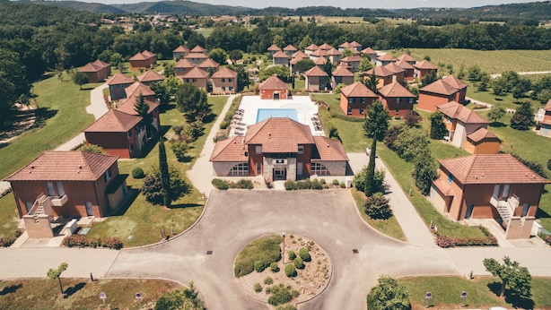 Vista aérea de una zona residencial con varias casas, una piscina central y abundante vegetación.