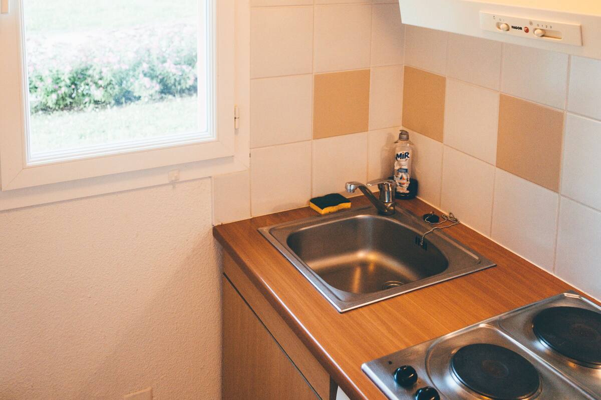 Une petite cuisine avec une fenêtre, un évier, une cuisinière et un lave-vaisselle.