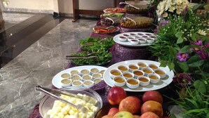 Une table de buffet proposant divers plats, notamment des assiettes de pommes, des bols de soupe et des récipients d’olives.