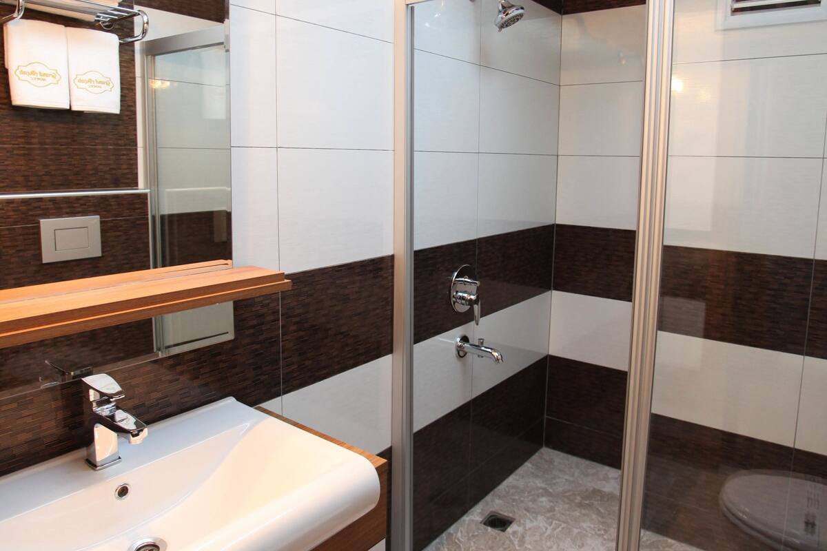 A modern bathroom with a glass shower enclosure, a vanity with a mirror, and a toilet.