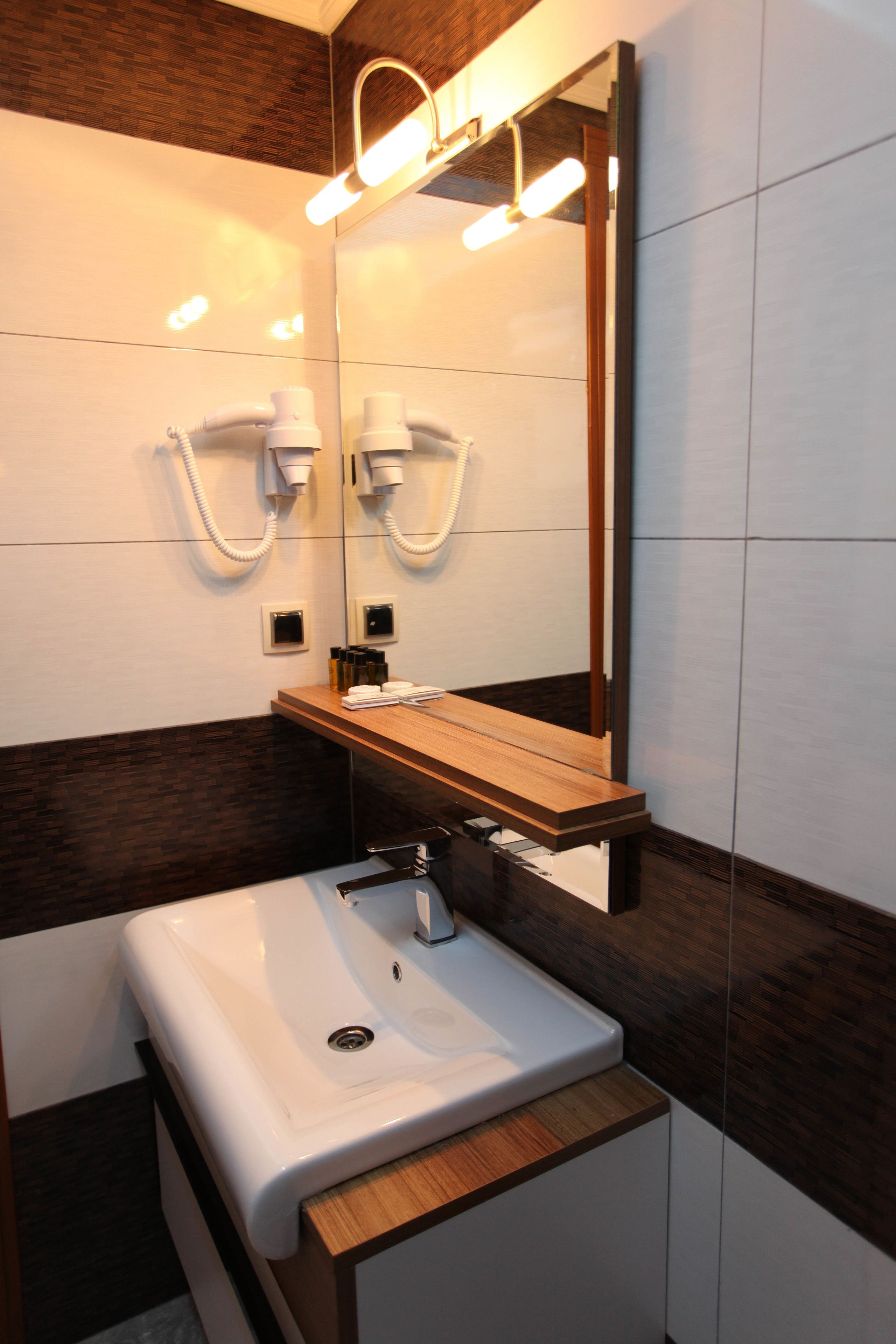 Un baño moderno con un lavamanos blanco, encimera de madera y espejo con iluminación integrada.