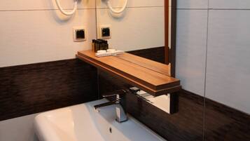 Un baño moderno con un lavamanos blanco, encimera de madera y espejo con iluminación integrada.