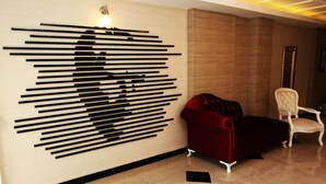 Un intérieur moderne agrémenté d’une œuvre d’art abstraite en noir et blanc accrochée au mur, d’un canapé en velours rouge et d’une chaise blanche.