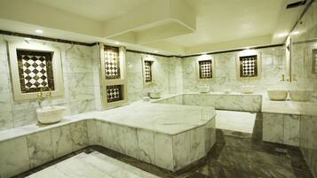 Bathroom features a large central sink and matching vanity, surrounded by decorative tiles with geometric patterns.
