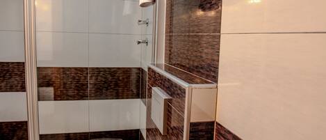 Un baño moderno con cabina de ducha de vidrio, inodoro y perchero.