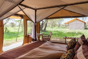 Um quarto tipo tenda, com uma cama, uma mesa e uma cadeira.