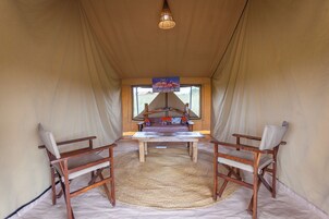 Uma tenda com uma mesa central e duas cadeiras, um candeeiro pendente e vista pela entrada.