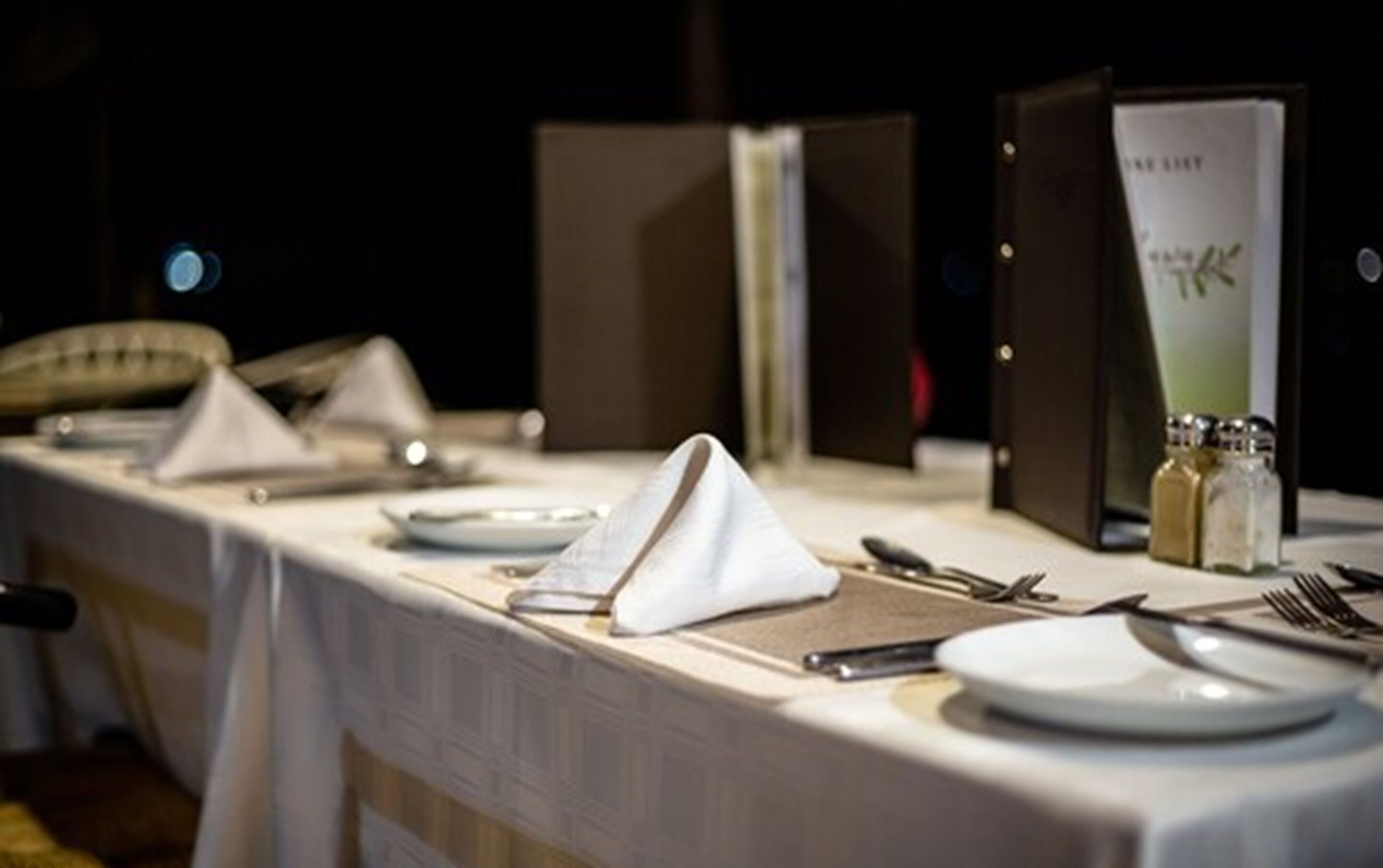 Een net gedekte eettafel met borden, bestek en servetten.