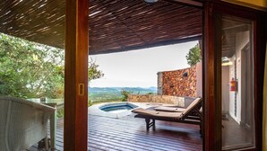 Una terraza exterior con un jacuzzi, sillones de descanso y vistas al paisaje.