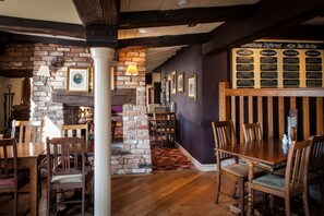 A restaurant interior with brick walls, wooden tables, and chairs. There is a menu board on the wall and a stone pillar. - Admiral's Table, Bridgwater by Marston's Inns (Bridgwater)