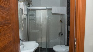 A bathroom with a glass-enclosed shower, a white sink, and a toilet.