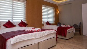A hotel room with two beds, each with red pillows and a white bedspread. There is a small table with a tray and a chair.