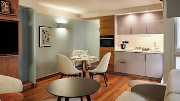 A modern living room with a round table and chairs, a sofa, and a kitchen area with cabinets and appliances.