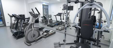 A modern gym with various exercise equipment including treadmills, elliptical machines, and weight machines.