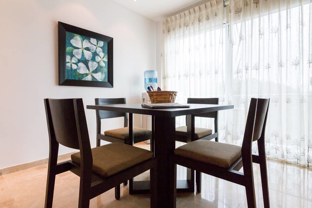 A dining area with a round table, four chairs, a framed artwork, a water dispenser, and a basket on the table.