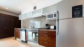 A modern kitchen with a stainless steel refrigerator, a microwave, a built-in oven, a dishwasher, and a coffee maker. - Papaya 20 by CocoBR (Playa del Carmen)