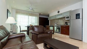 A modern living room with a leather sofa, a recliner, and a coffee table. The kitchen features stainless steel appliances and a granite countertop. - Papaya 20 by CocoBR (Playa del Carmen)